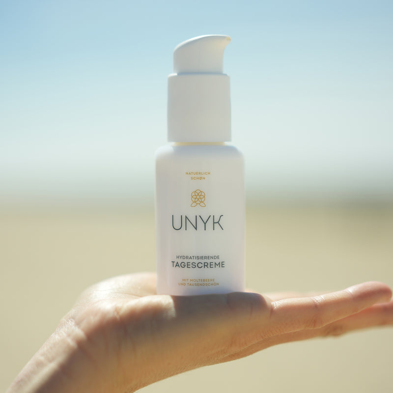 UNYK Tagescreme steht in der Hand.Tagescreme von UNYK Cosmetics steht in der Hand. Ein Hyaluronsäure-Komplex spendet Feuchtigkeit und glättet die Hautoberfläche.